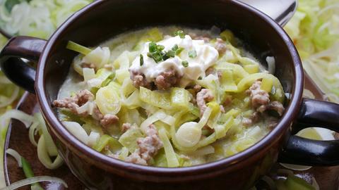 Käse-Lauch-Hack-Suppe in einem dunkel glasierten Schälchen.