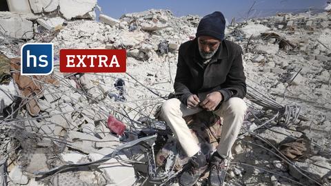 Ein Mann sitzt auf den bodend blickend auf den Trümmern seines Hauses. Auf dem Bild: hessenschau EXTRA-Logo