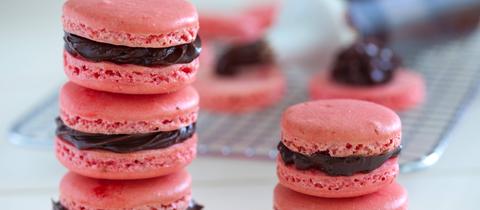 Aufeinandergestapelte rosarote Macarons mit Schokoladenfüllung.