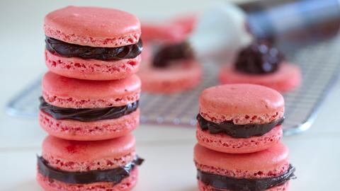 Aufeinandergestapelte rosarote Macarons mit Schokoladenfüllung.