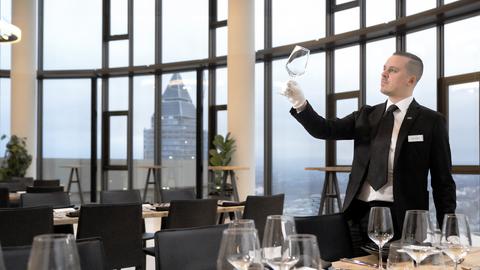 Ein Mann kontrolliert die Sauberkeit der Weingläser im Restaurant des Tower 185. 