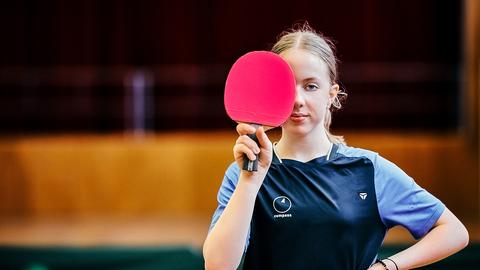 Josi Neumann hält sich einen Tischtennisschläger halb vor das Gesicht