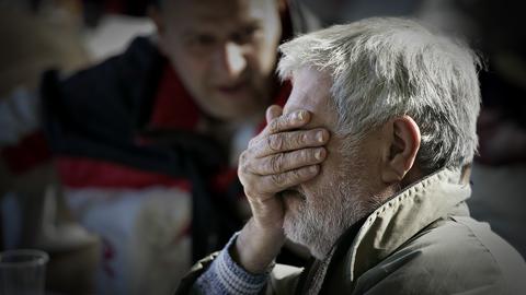 Ein alter von Armut betroffener Mann hält sich die Hand vor die Augen.