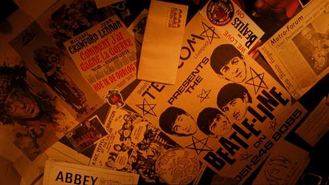 Verschiedene Plakate an der Wand, davon auch ein Plakat der Beatles.