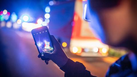 Symbolbild von einem Gaffer mit seinem Smartphone bei einem Feuerwehr/Rettungsdiensteinsatz.