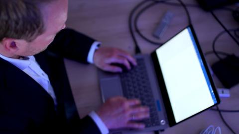 Ein Mann sitzt vor seinem Laptop und tippt auf der Tastatur.
