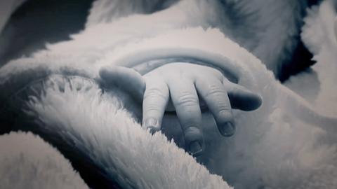 Eine babyhand schaut aus einer Decke