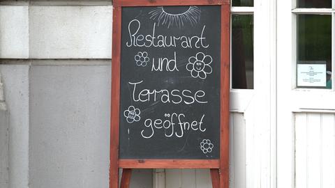 Ein Schild vor einem Restaurant mit der Aufschrift "Restaurant und Terrasse geöffnet". 