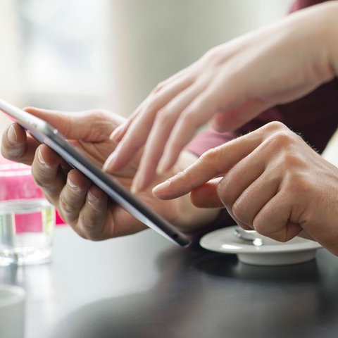 Paar verwendet ein Tablet gemeinsam im Cafe. 