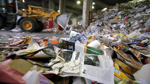 Gesammeltes Altpapier auf dem Firmengelände der Rauch Recycling GmbH. Im Hintergrund ist ein Bagger zu sehen.