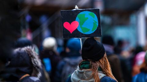 Demonstrantin hält Protestplakat hoch.