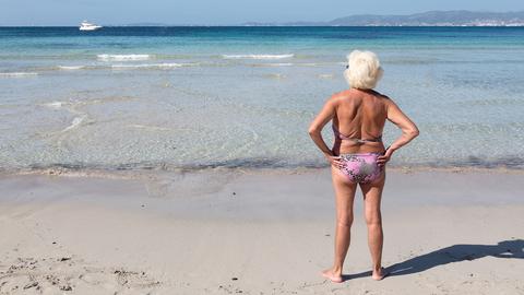 Ältere Frau im Bikini am Strand. 