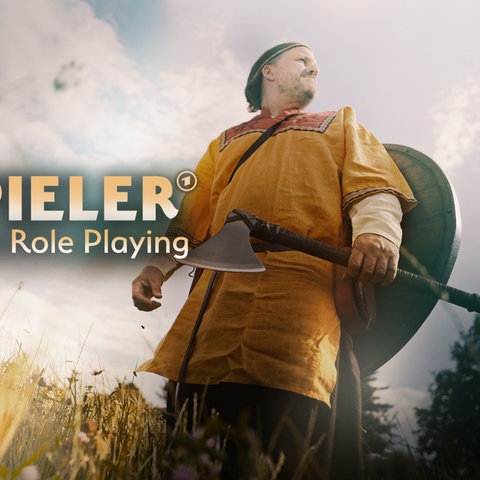 Ein Mann in Verkleidung mit Beil und Schild in einem Feld. Logo: Weltenspieler / Text: Faszination Live Action Role Playing