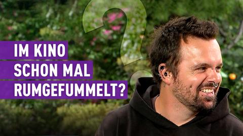 Mann mit vielen Piercings im Gesicht schaut zur Seite und lacht. Text: Im Kino schon mal rumgefummelt?