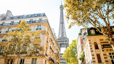 Blick auf den Eifelturm aus einer klassischen Pariser Straße mit Altbauten. 