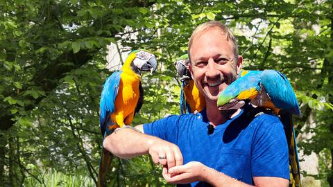 Tobi Kämmerer mit Papagei auf dem Arm.