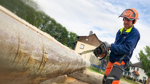 Holz-Fan Michael Opper sägt mit seiner Kettensäge an einem Baumstamm.