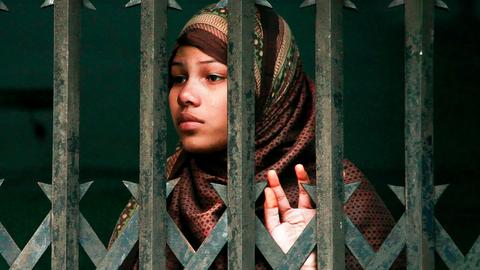Eine weinende Zwangsprostituierte aus Bangladesch hinter Gittern. 