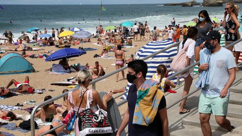 Strandbesucher halten sich mit Mund-Nasen-Bedeckung am Strand von Biarritz, Frankreich, auf.