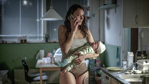 Jenni (Josefine Asplund) hält ihr Baby im Arm. 