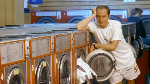 Der hessische Kult-Moderator Holger Weinert lehnt sich an einer Waschmaschine an