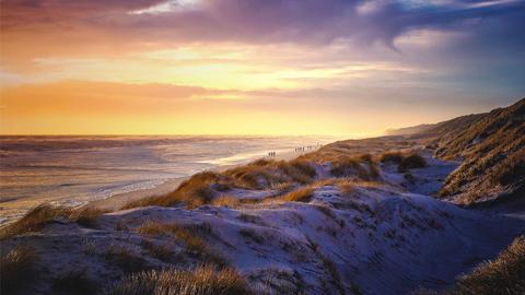 Spaziergänger beim Sonnenuntergang an der dänischen Küste. Mystische Lichtstimmung.