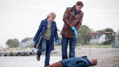 Der Lübecker Marzipanfabrikant Lübbers (Reent Reins, liegend) liegt tot am Timmendorfer Strand. Finn Kiesewetter (Sven Martinek, r.) und Kollegin Sandra Schwartenbeck (Marie Luise Schramm, l.) nehmen die Ermittlungen auf.