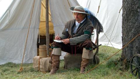 Der Söldner Peter Hagendorf sitzt im Lager und macht sich Notizen für sein Tagebuch.