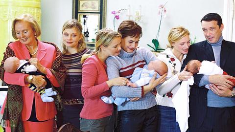 Fünf Frauen und ein Mann halten insgesamt drei Babys im Arm. 