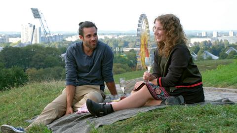 Enzo (Deniz Arora) und Jella (Antonia Bill) sitzen gemeinsam auf eine Wiese. 