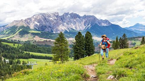 Wandererin auf dem Berg mit Gebirge im Hintergrund.