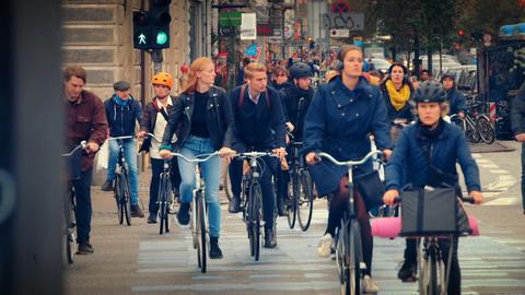 Viele Menschen fahren auf ihren Fahrrädern über einen grünen Verkehrsampelweg. 