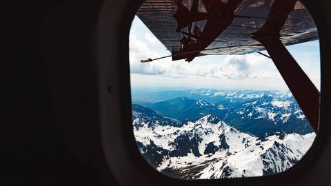 Wasserflugzeug fliegt über schneebedeckte Berge.