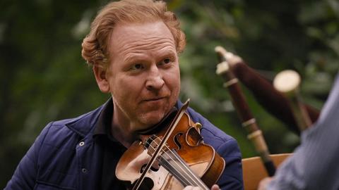 Musiker Daniel Hope spielt konzentriert mit seiner Geige in der Natur.