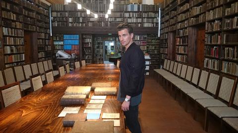 Julian Sengelmann wühlt sich in einer Bibliothek durch alte Akten. 