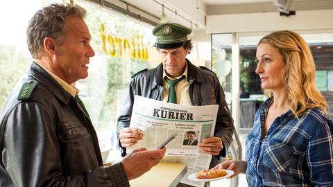Hubert (Christian Tramitz, l.) und Staller (Helmfried von Lüttichau, M.) erfahren von der frisch gebackenen Ladenbesitzerin Barbara Hansen (Monika Gruber, r.), dass der Tote ein notorischer Schürzenjäger war.