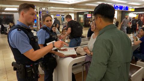 Zwei Polizist*innen kontrollieren zwei Tourist*innen am Flughafen