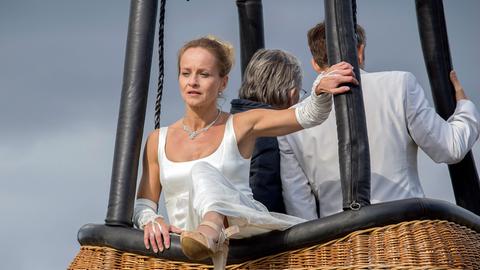 Aus nicht nachvollziehbaren Gründen klettert die Braut Susanne Kröning (Christine Kutschera) plötzlich aus dem Korb und stürzt ab.