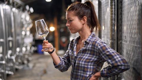 Bio-Winzerin Anne (Henriette Richter-Röhl) in einem Weinkeller mit einem Weinglas in der Hand.