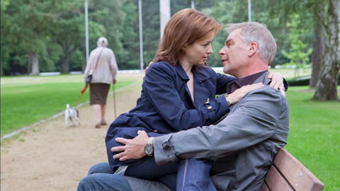 Nora (Loretta Stern, l.) und Jon (Frank Vockroth, r.) schmusen auf einer Parkbank.