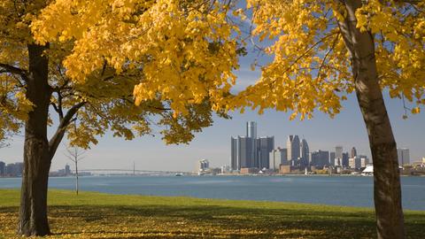 Stadtzentrum von Detroit am Detroit River umrahmt von herbstlichen Bäumen.