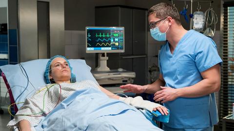 Ein Arzt beruhigt eine Frau in einem Krankenbett kurz vor ihrer OP.