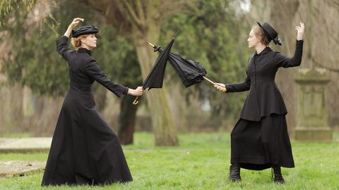 Zwei Frauen duellieren sich mit einem Regenschirm