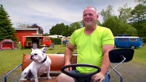 Sven Bettermann sitzt mit seinem Hund auf einem motorbetriebenen Wagen.