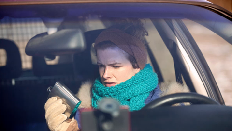 Emily Gans (Mira Bartuschek) durchsucht ein Auto, sie hält einen Flachmann in der Hand.