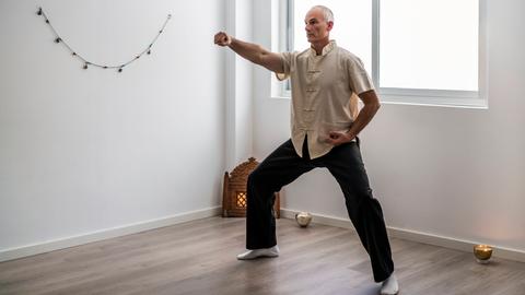 Ein älterer Mann praktiziert eine Qi-Gong-Übung.