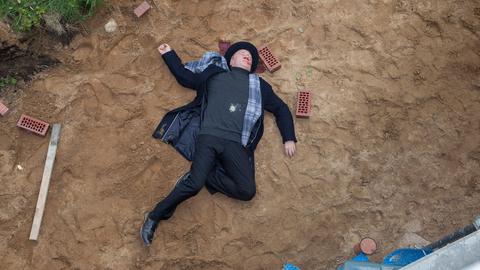 Ein schwarz gekleideter Mann liegt tot im Sand.