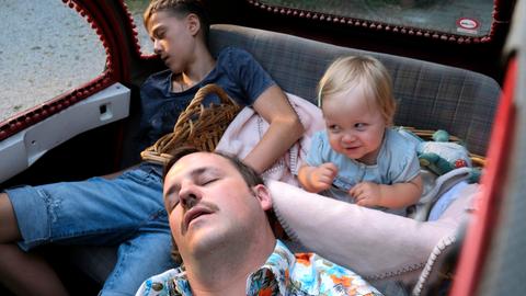 Ein Mann und zwei Kinder schlafen auf der Rückbank eines Autos