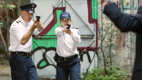 Zwei Polizisten richten ihre Waffe auf einen Verdächtigen
