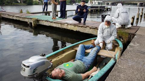 Polizisten untersuchen einen toten Mann in einem Ruderboot